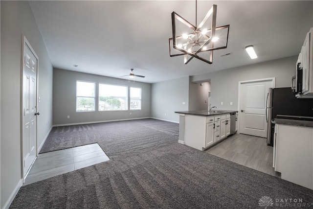 kitchen with pendant lighting, dishwasher, light carpet, ceiling fan with notable chandelier, and white cabinetry