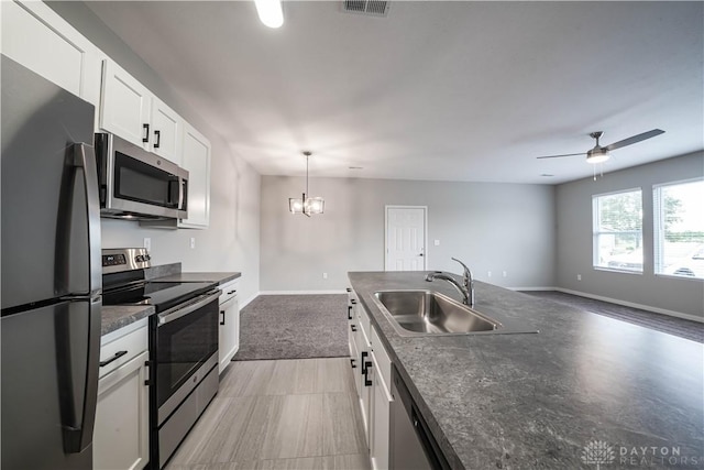 kitchen with white cabinetry, sink, hanging light fixtures, ceiling fan with notable chandelier, and appliances with stainless steel finishes