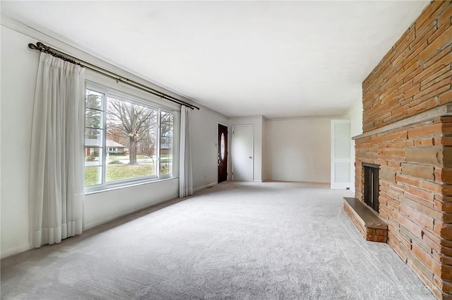 unfurnished living room featuring light colored carpet, a stone fireplace, and a wealth of natural light