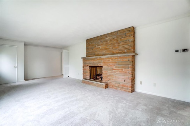 unfurnished living room with a stone fireplace, crown molding, and carpet