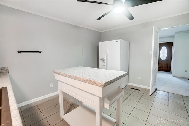 kitchen featuring white refrigerator with ice dispenser, light tile patterned floors, ceiling fan, and ornamental molding