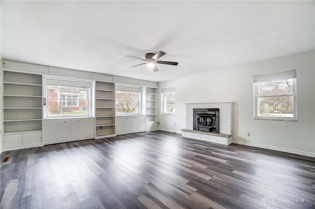 unfurnished living room with ceiling fan, dark hardwood / wood-style floors, and a brick fireplace