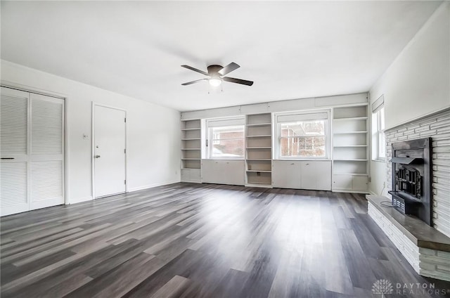 unfurnished living room with ceiling fan, dark wood-type flooring, and a wealth of natural light