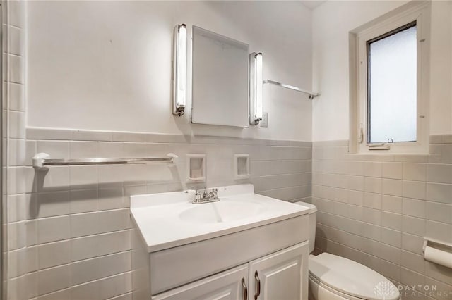 bathroom featuring vanity, tile walls, and toilet