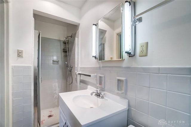 bathroom featuring a tile shower, vanity, and tile walls