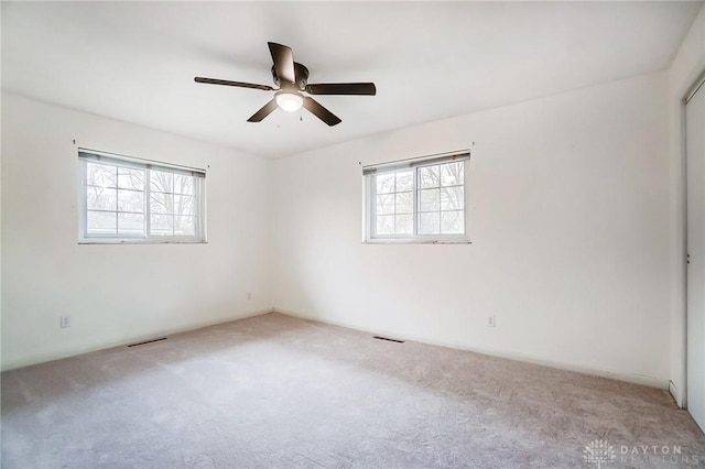 carpeted empty room featuring a wealth of natural light and ceiling fan