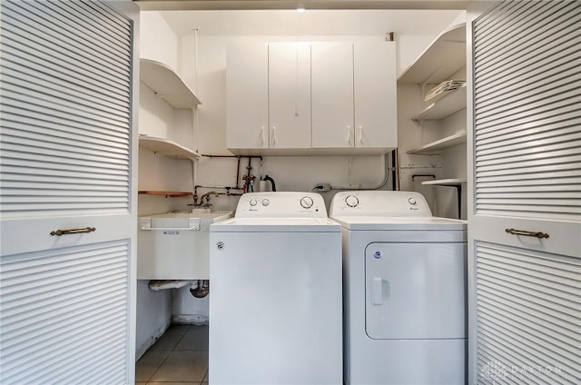 laundry area with cabinets, light tile patterned floors, washing machine and dryer, and sink