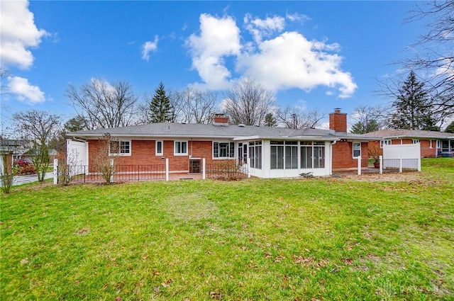 back of property with a sunroom and a yard