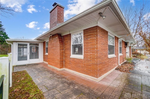 view of side of home with a patio area and a sunroom