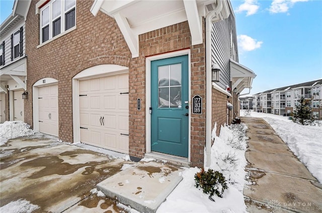 snow covered property entrance featuring a garage