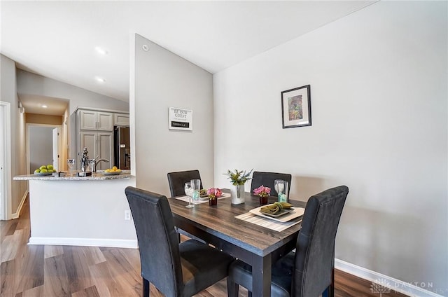 dining room with wood-type flooring and vaulted ceiling