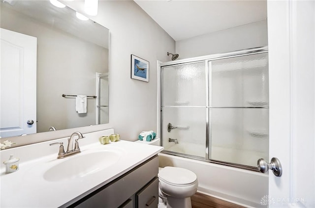 full bathroom featuring toilet, vanity, bath / shower combo with glass door, and hardwood / wood-style flooring