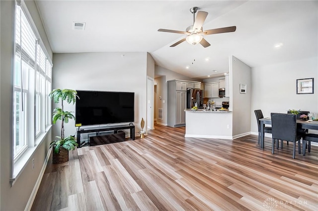 living room with light hardwood / wood-style floors, a wealth of natural light, lofted ceiling, and ceiling fan