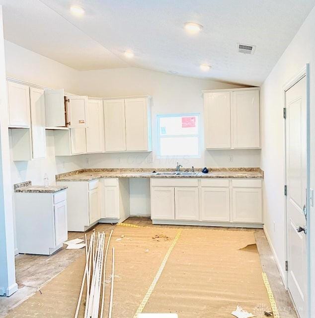 kitchen featuring lofted ceiling, white cabinetry, visible vents, and light wood finished floors