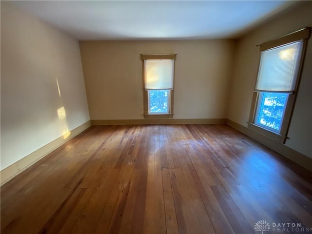 empty room with a wealth of natural light and hardwood / wood-style floors