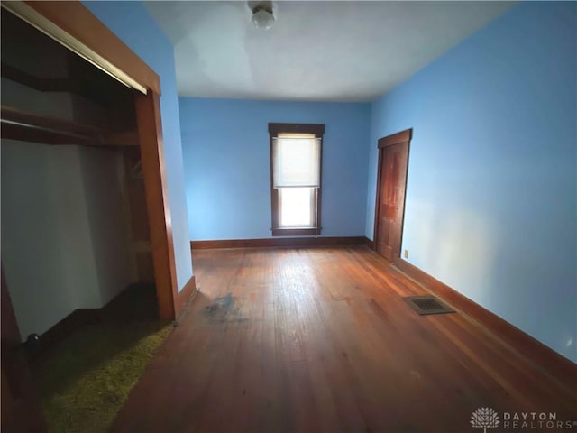 unfurnished bedroom featuring a closet and dark wood-type flooring