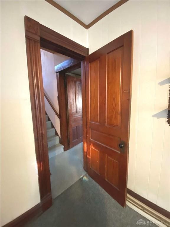 hallway with crown molding and dark carpet