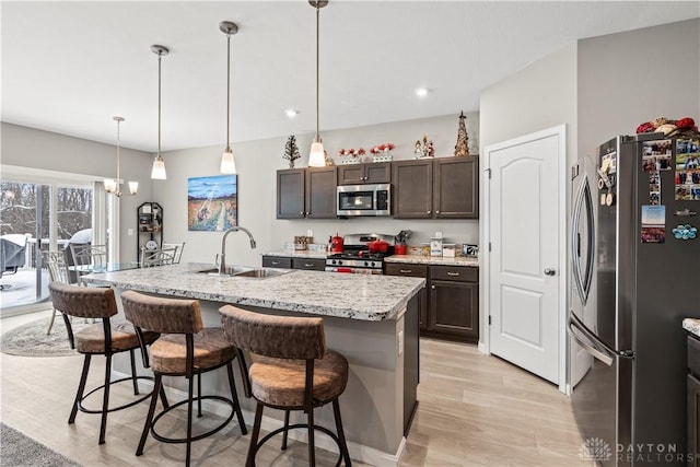1189 Heathgate Way, Fairborn, OH 45324 - kitchen featuring a breakfast bar area, light wood-style flooring, a sink, dark brown cabinetry, and appliances with stainless steel finishes