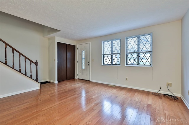 entryway with light wood-type flooring and a textured ceiling