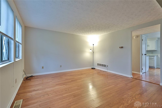 empty room with light hardwood / wood-style flooring and a textured ceiling