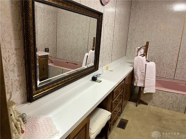 bathroom with vanity and tiled tub