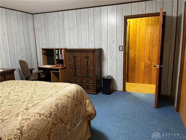 bedroom with carpet flooring, wooden walls, and ornamental molding