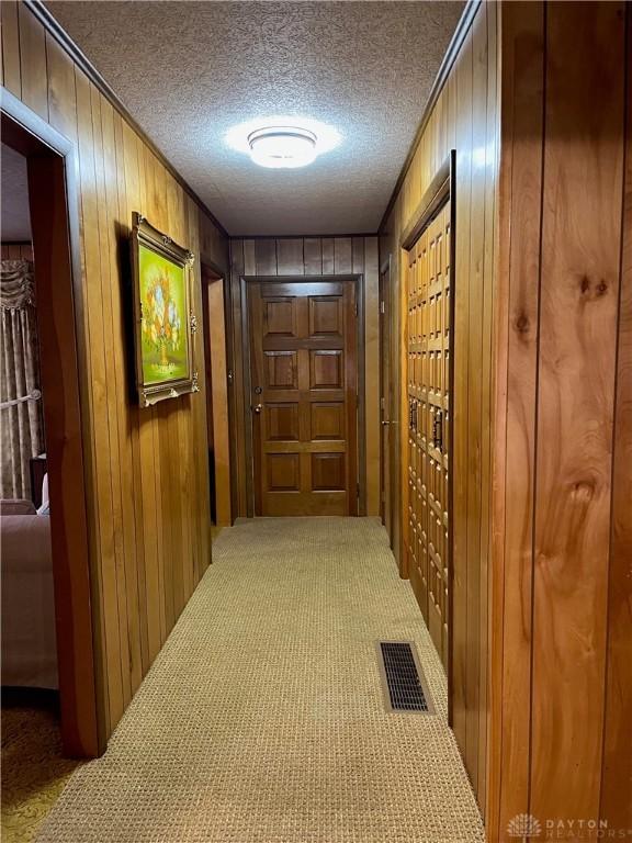 hallway with carpet flooring, mail boxes, a textured ceiling, and wooden walls