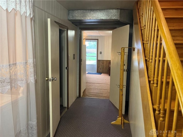 hall with carpet flooring and wooden walls