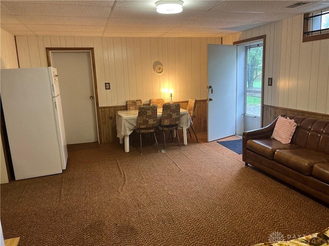 carpeted living room with wood walls