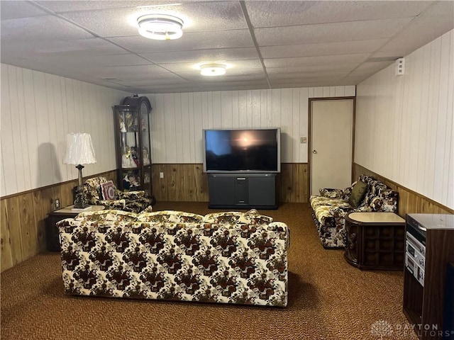 carpeted living room featuring a paneled ceiling and wooden walls