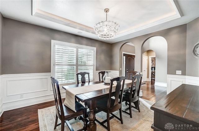 dining space featuring hardwood / wood-style floors, an inviting chandelier, and a raised ceiling