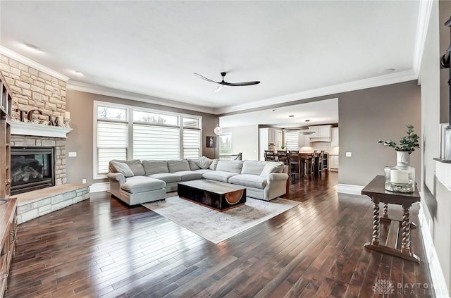 living room featuring plenty of natural light, a stone fireplace, ceiling fan, and crown molding