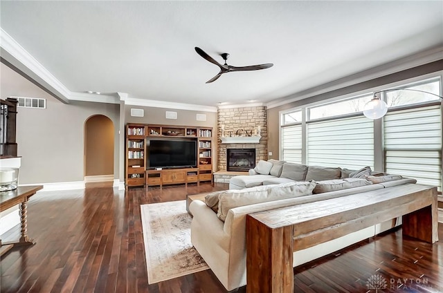 living room featuring a fireplace, dark wood-type flooring, ceiling fan, and crown molding