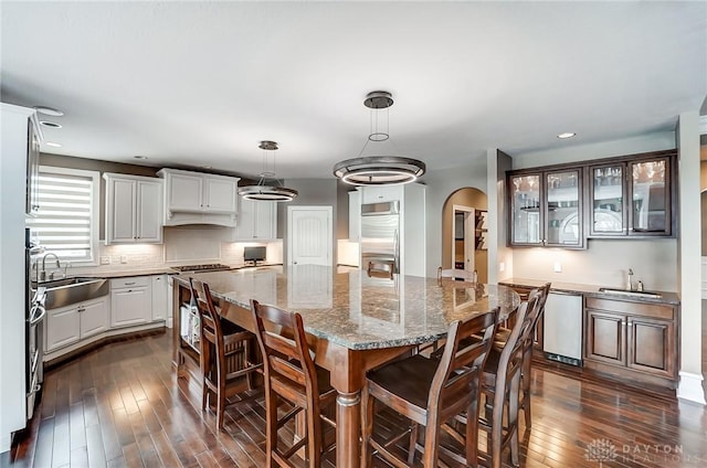 kitchen with white cabinets, a center island, decorative light fixtures, and built in appliances