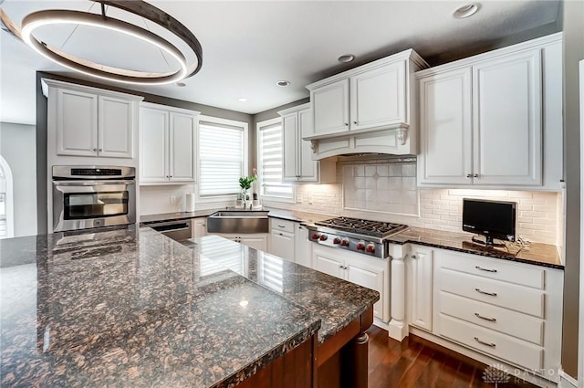 kitchen with white cabinets, sink, stainless steel appliances, and dark stone counters