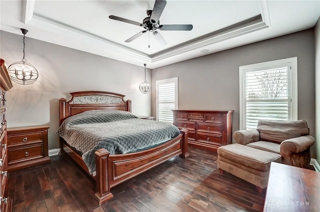 bedroom featuring dark hardwood / wood-style flooring, ceiling fan with notable chandelier, and a raised ceiling