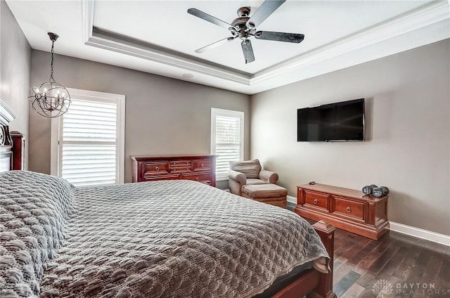 bedroom featuring ceiling fan with notable chandelier, a tray ceiling, crown molding, and dark wood-type flooring