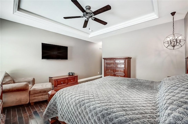 bedroom featuring ceiling fan with notable chandelier, dark hardwood / wood-style floors, a raised ceiling, and ornamental molding