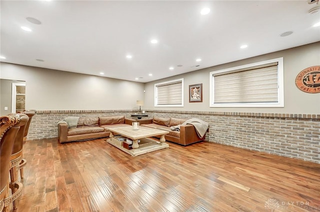 living room with light hardwood / wood-style floors and brick wall