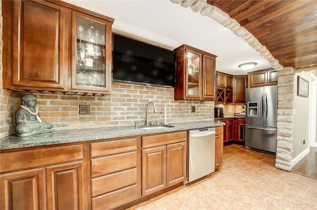 kitchen with light stone countertops, appliances with stainless steel finishes, tasteful backsplash, sink, and wooden ceiling