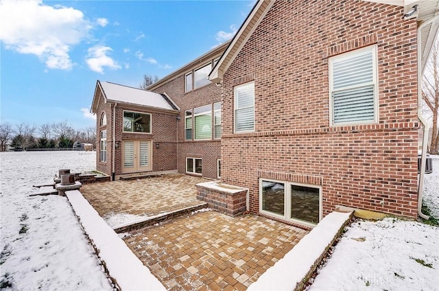 snow covered property featuring a patio