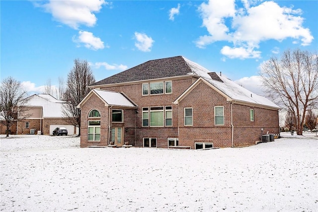 snow covered house featuring central AC