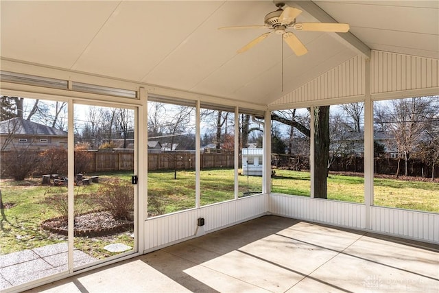 unfurnished sunroom featuring ceiling fan, plenty of natural light, and lofted ceiling with beams