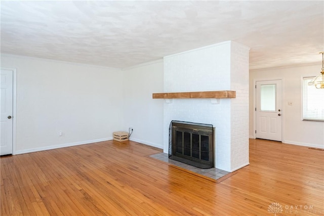 unfurnished living room featuring a fireplace, light hardwood / wood-style flooring, and crown molding