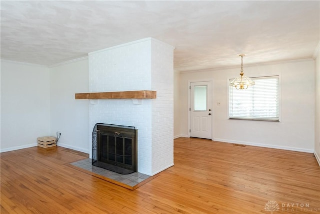 unfurnished living room with a chandelier, a fireplace, ornamental molding, and light hardwood / wood-style flooring