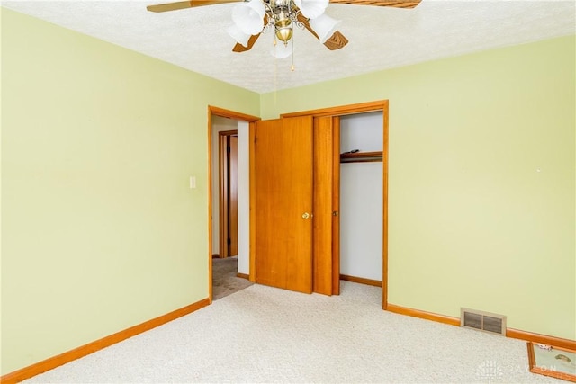 unfurnished bedroom with light carpet, a textured ceiling, a closet, and ceiling fan