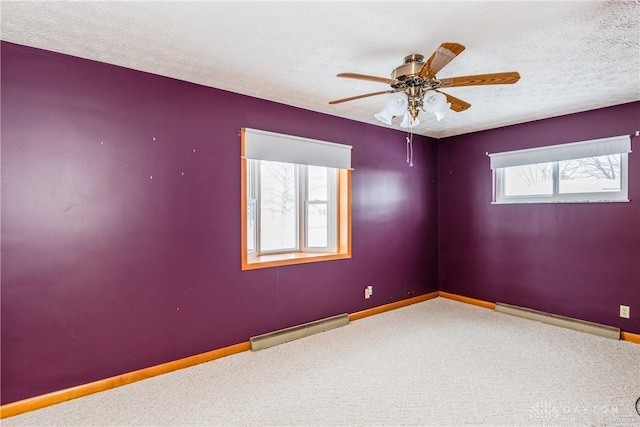 spare room with ceiling fan, carpet floors, a baseboard radiator, and a textured ceiling