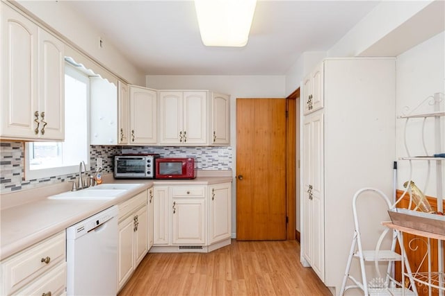 kitchen featuring decorative backsplash, sink, light hardwood / wood-style flooring, dishwasher, and white cabinetry