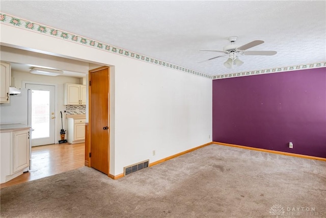 carpeted spare room featuring a textured ceiling and ceiling fan