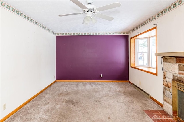 carpeted spare room featuring a textured ceiling, a stone fireplace, ceiling fan, and a baseboard heating unit